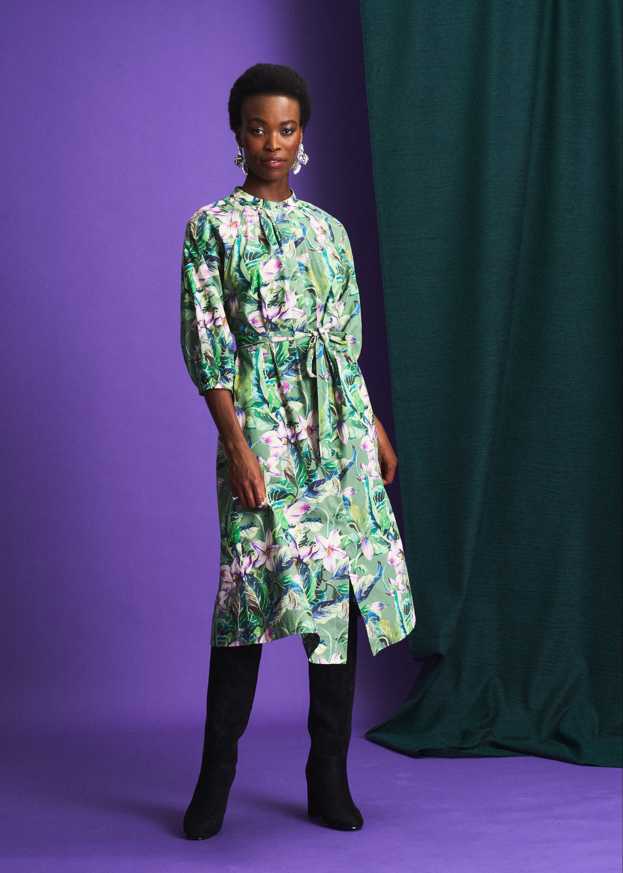Woman wearing a floral dress against a purple and green backdrop