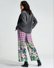 Person wearing a gray sweater and pink floral pants on a white background