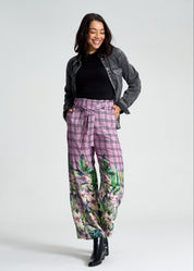 Woman wearing a gray jacket, black top, and floral pants on a white background