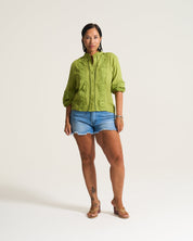 Woman wearing a green jacket and denim shorts on a white background