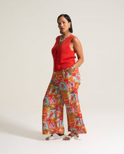 Woman wearing a red top and colorful patterned pants on a white background