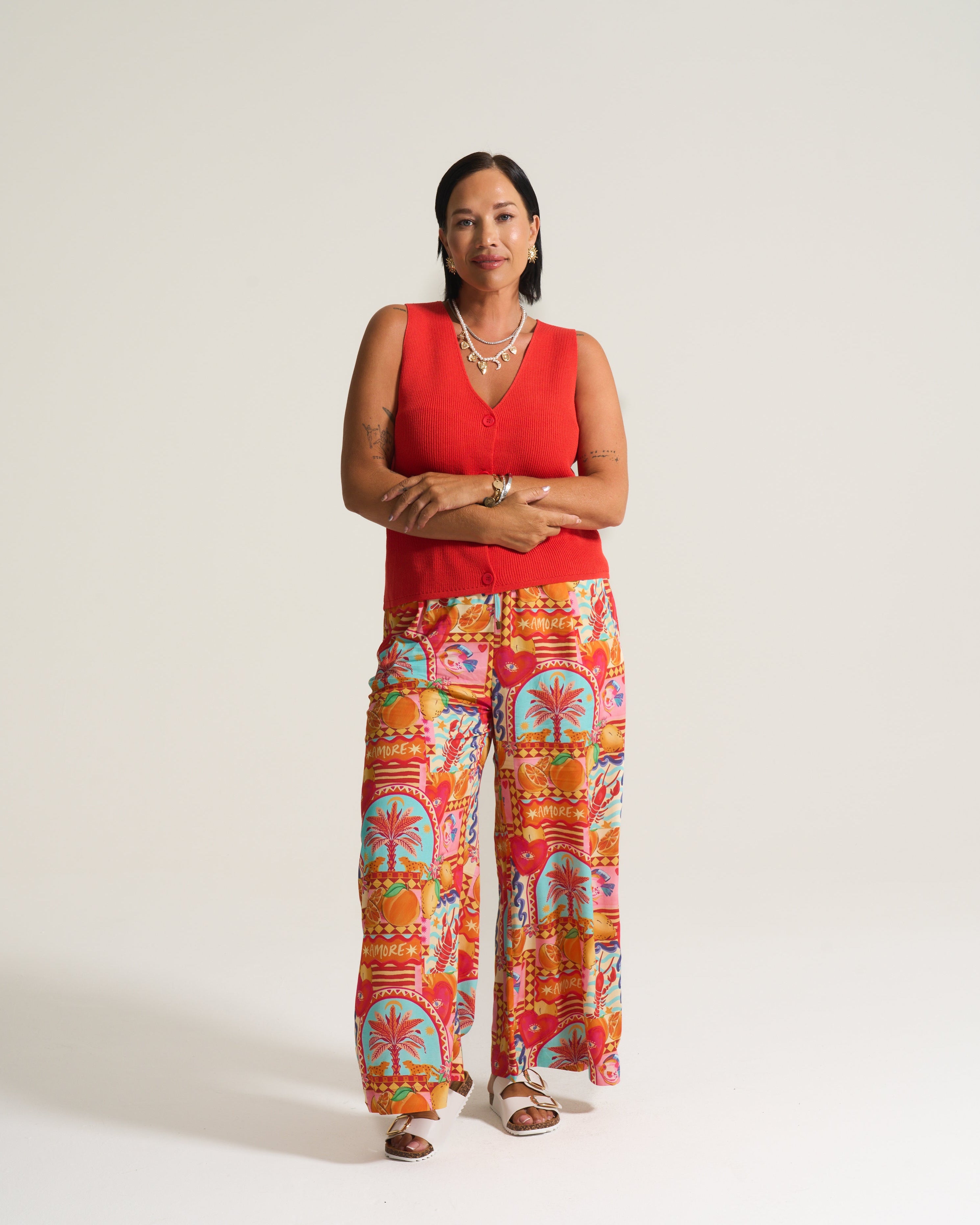 Woman wearing a red top and colorful patterned pants on a white background