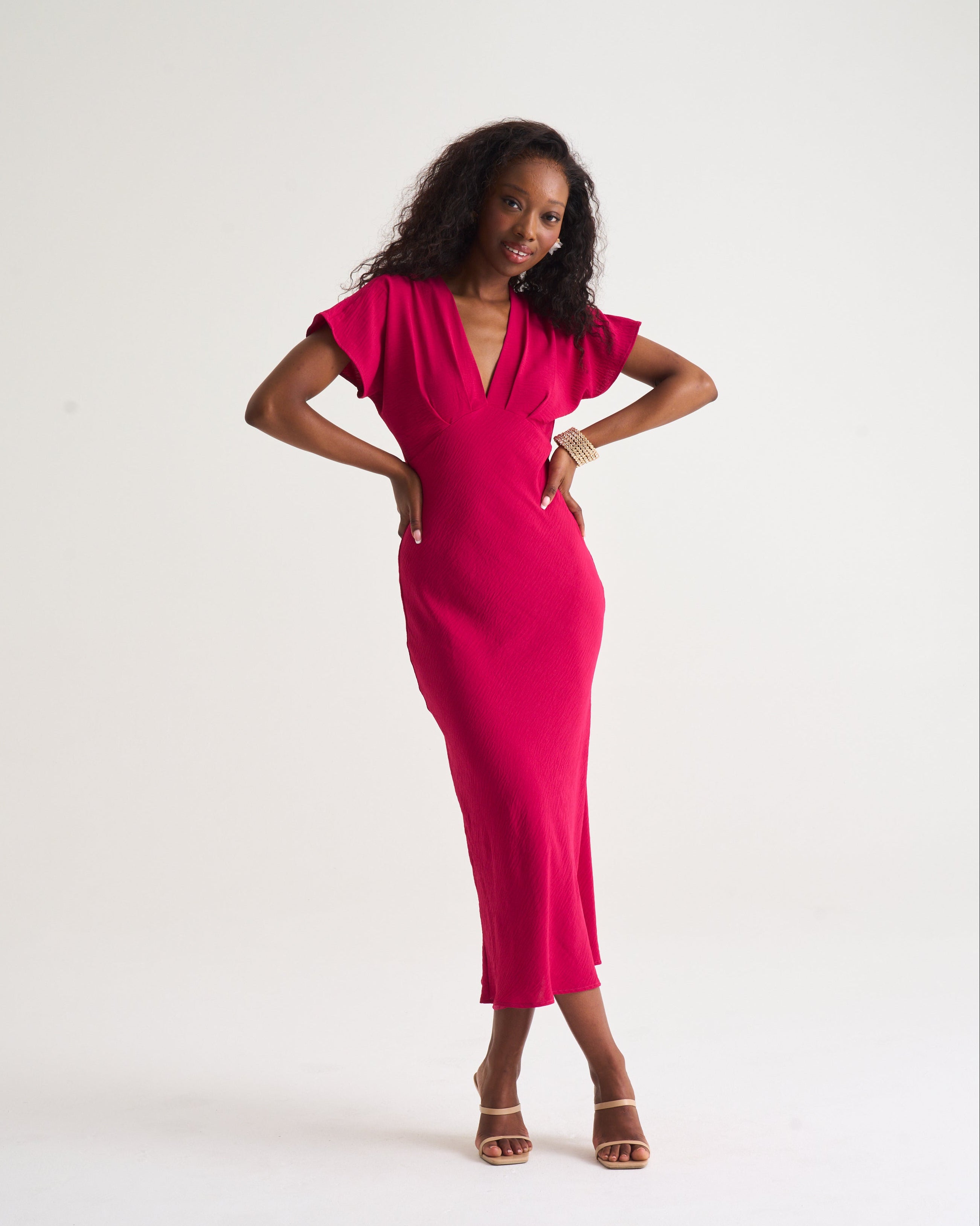 Woman wearing a bright pink dress against a white background