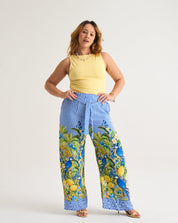 Woman wearing a yellow sleeveless top and lemon floral pants on a white background