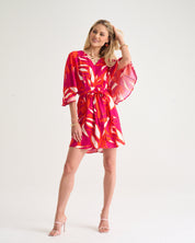 Woman wearing a vibrant pink and orange dress on a white background