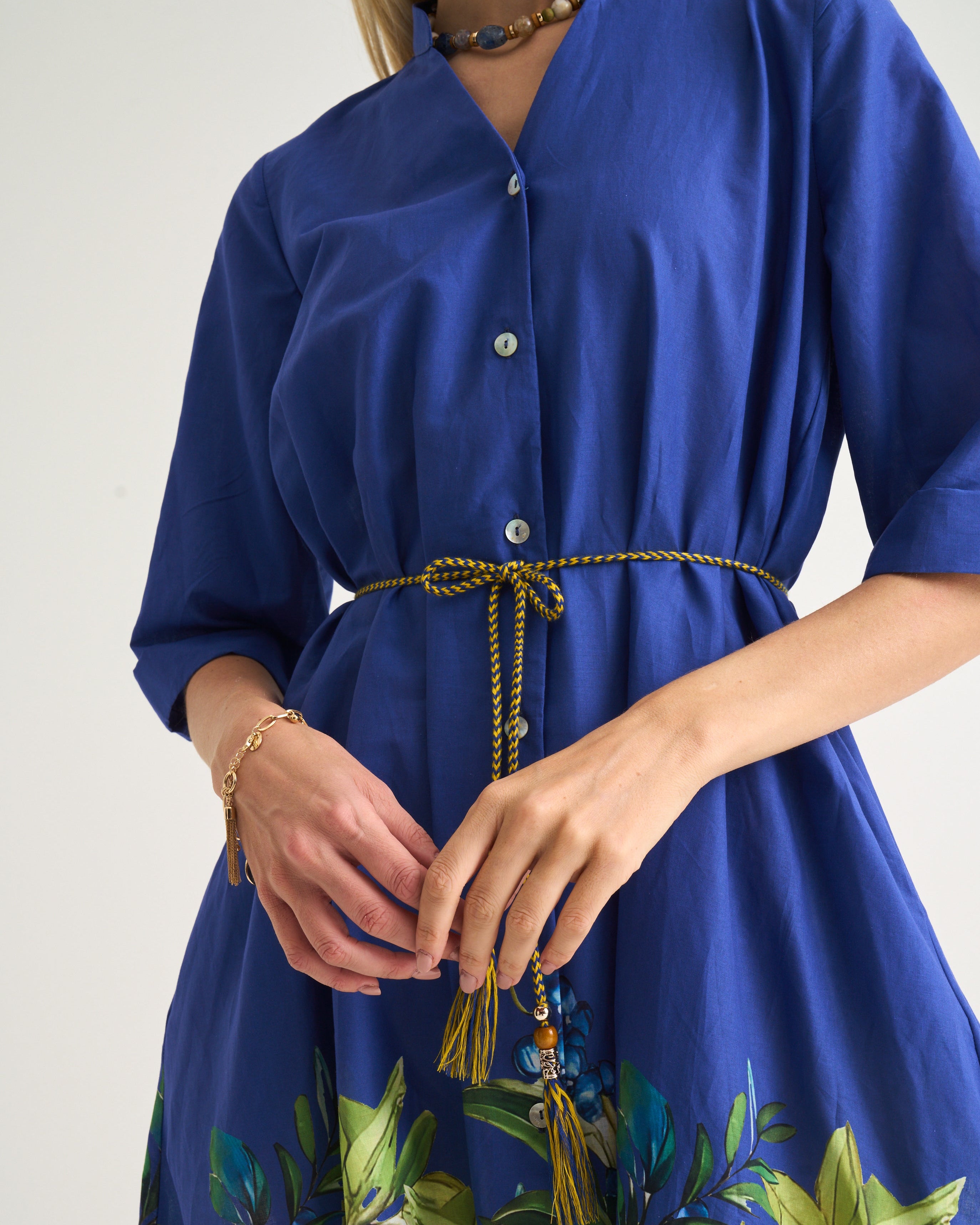 Blue dress with floral pattern and tassel detail on a plain background